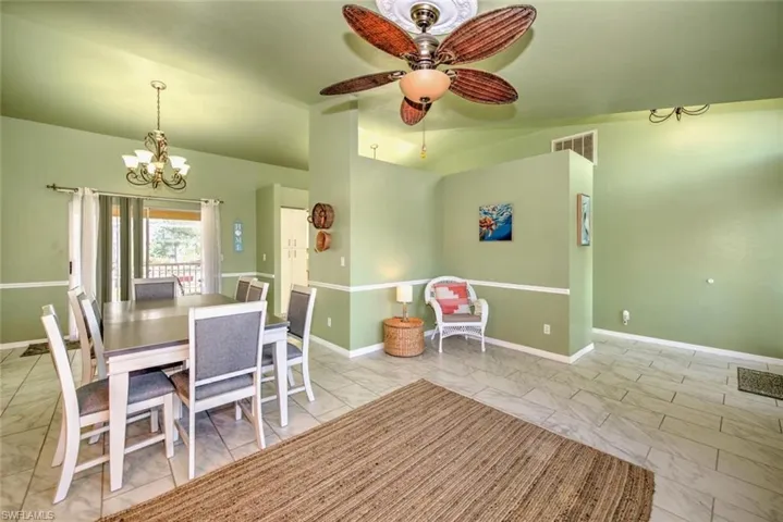 Dining area featuring lofted ceiling, a chandelier, ceiling fan, and light marble finish flooring