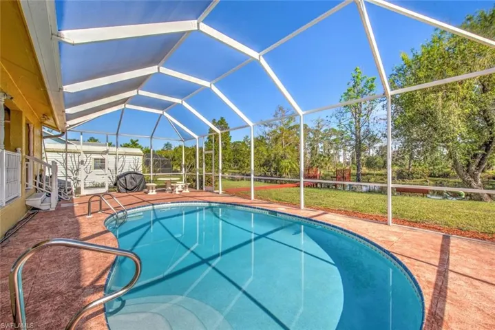 Outdoor pool with a lanai, a sunroom, a patio area, and a yard