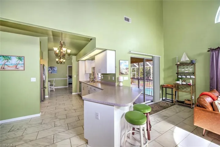Kitchen with decorative light fixtures, light marble finish flooring, a peninsula, a chandelier, and a breakfast bar