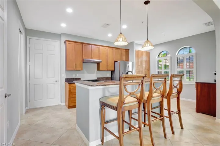 Kitchen with a kitchen bar, stainless steel appliances, light tile patterned floors, and kitchen island