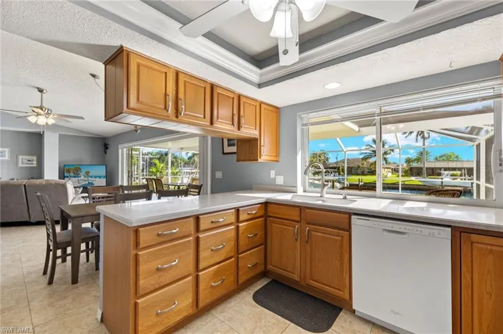 Kitchen with kitchen peninsula, a textured ceiling, ceiling fan, sink, and dishwasher