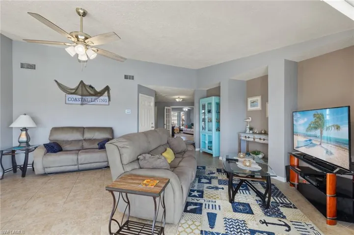 Living room featuring ceiling fan, light tile patterned floors, and a textured ceiling