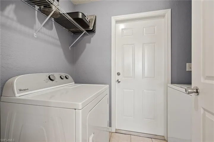 Laundry area with light tile patterned flooring and washer and dryer