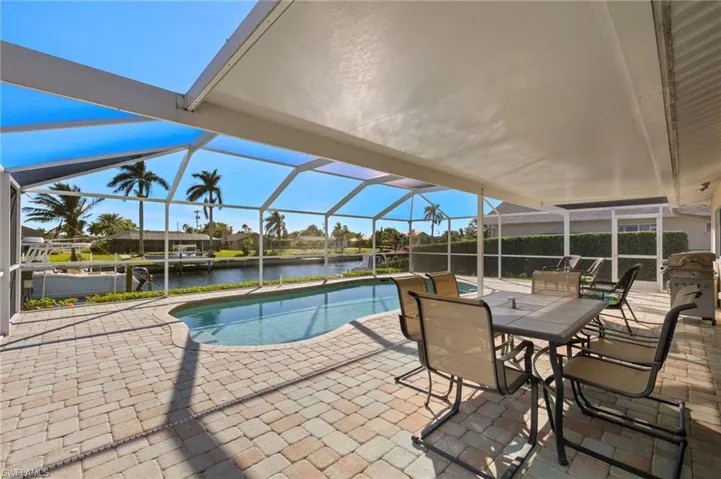 View of pool featuring glass enclosure, a patio area, and a water view