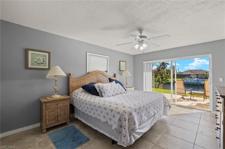 Bedroom featuring access to exterior, ceiling fan, light tile patterned flooring, a textured ceiling, and a water view