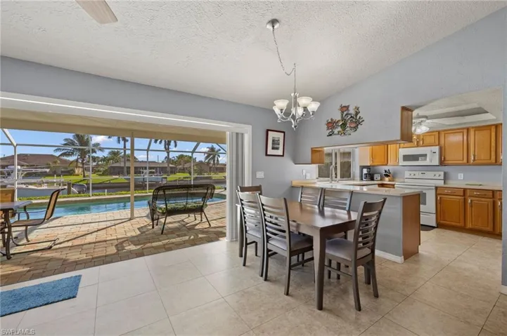 Dining space featuring a textured ceiling, light tile patterned flooring, and ceiling fan with notable chandelier
