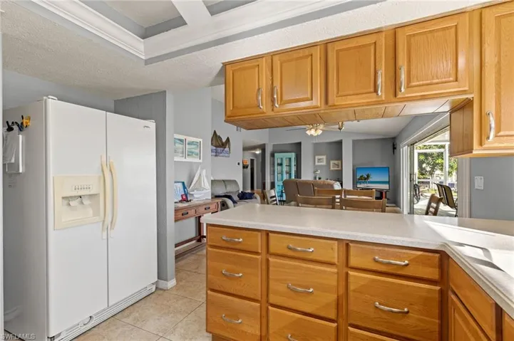 Kitchen featuring ceiling fan, white fridge with ice dispenser, a textured ceiling, and light tile patterned floors