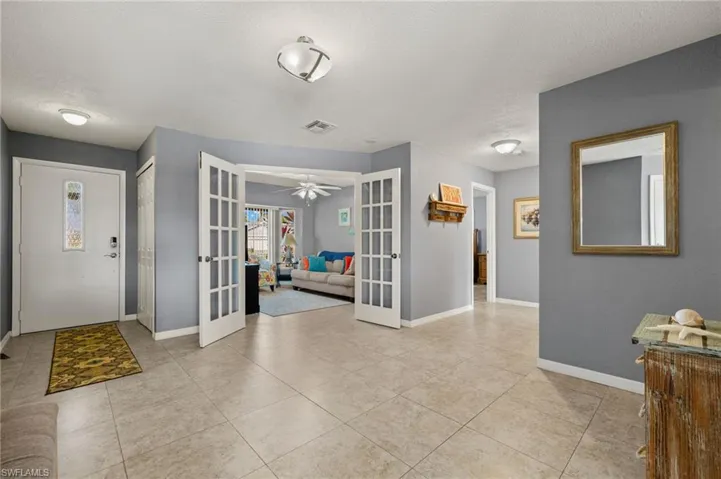 Foyer featuring ceiling fan, french doors, light tile patterned floors, and a textured ceiling
