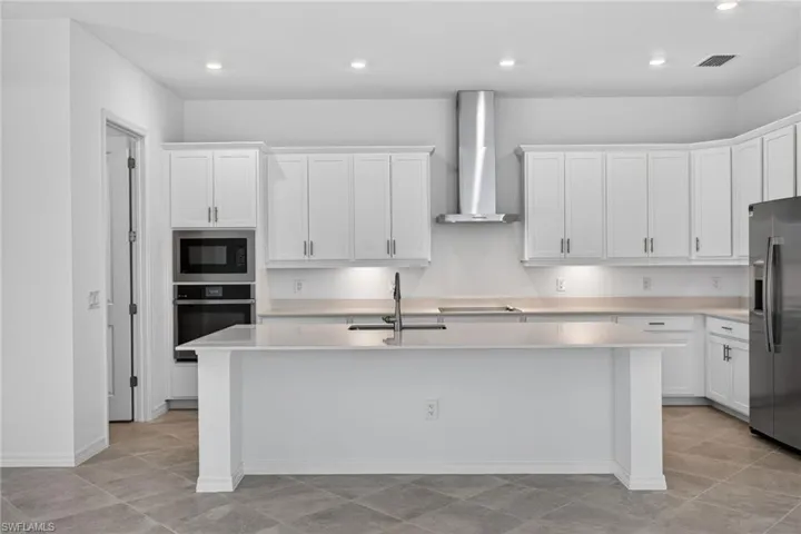 Kitchen featuring white cabinetry, stainless steel appliances, recessed lighting, and a kitchen island with sink