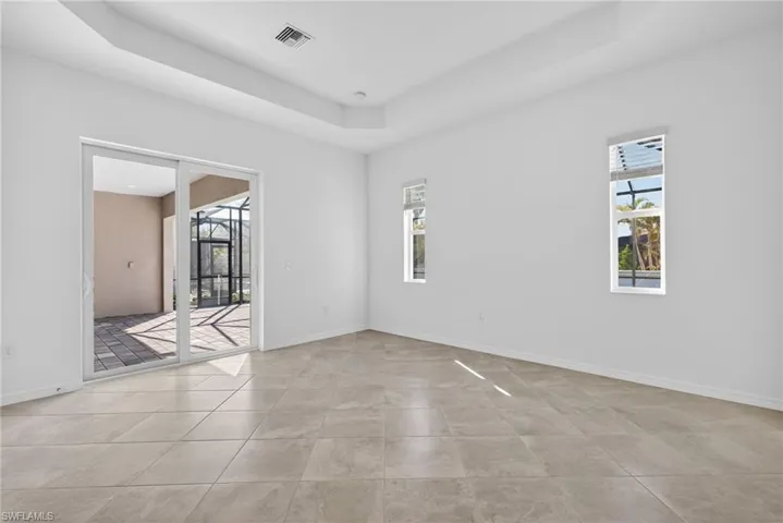 Primary Bedroom featuring a tray ceiling, a sunroom, and light tile patterned floors