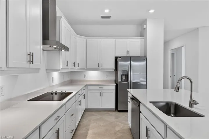 Kitchen with white cabinets, stainless steel appliances, light stone counters, and recessed lighting