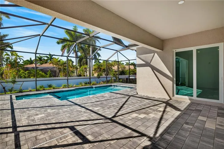 Outdoor pool featuring a patio area, a sunroom, and glass enclosure