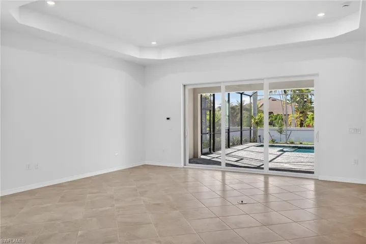 Family room with a raised ceiling, recessed lighting, and light tile patterned flooring