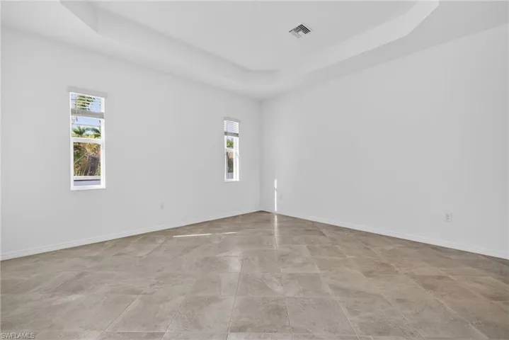 Primary Bedroom featuring a tray ceiling and baseboards