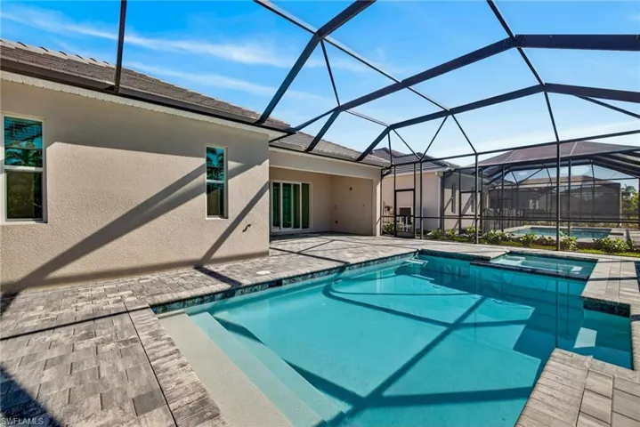 Relaxing pool / spa with a sunroom, a patio area, and a lanai