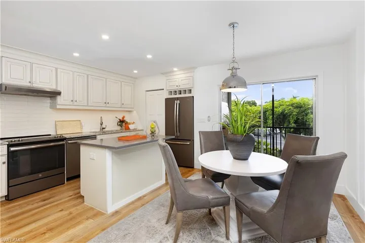 Kitchen with white cabinetry, pendant lighting, light hardwood / wood-style floors, appliances with stainless steel finishes, and backsplash