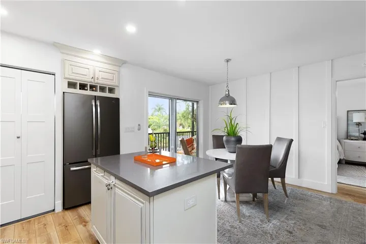 Kitchen with light hardwood / wood-style floors, stainless steel refrigerator, white cabinetry, and a kitchen island