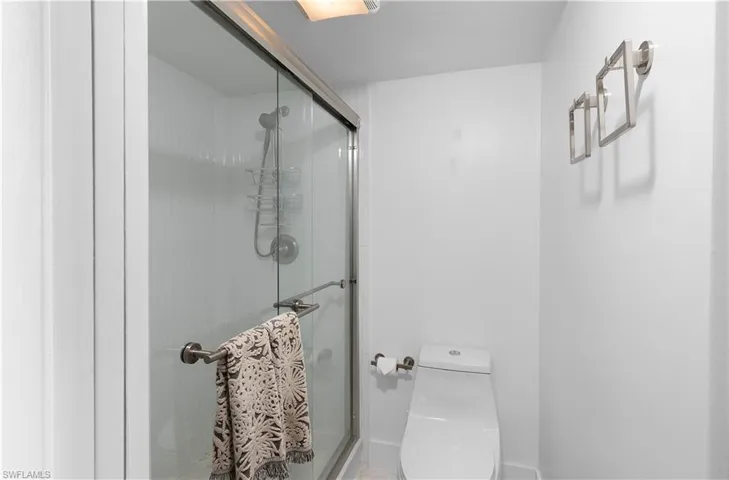 Bathroom featuring a shower with shower door and toilet