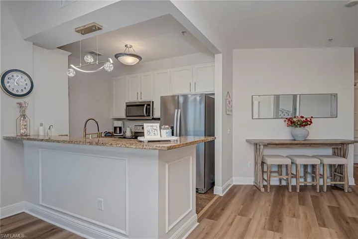 Kitchen featuring stainless steel appliances, white cabinets, light tile patterned floors, and light stone countertops