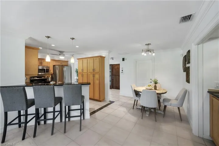 Kitchen featuring light wood cabinetry, granite countertops, stainless steel appliances, a breakfast nook and tile flooring.