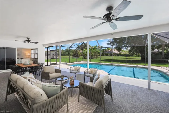 Screened lanai featuring a swimming pool, covered seating area, ceiling fans, and a large dining space