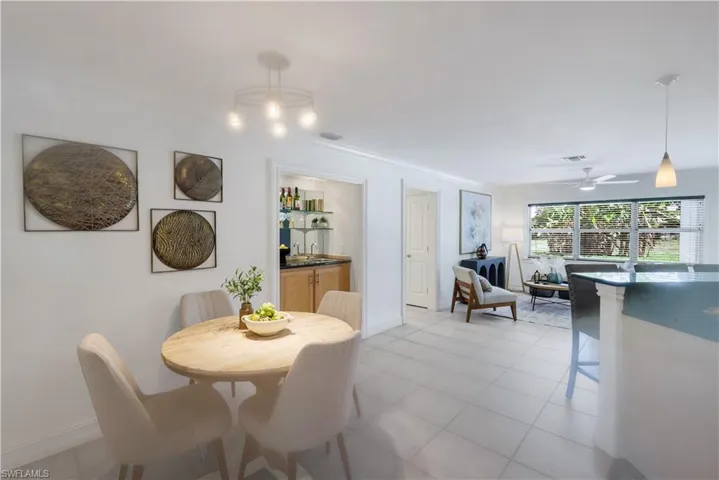 Breakfast nook (additional dining area), chandelier and a built-in wet bar with wood cabinetry and glass shelving.