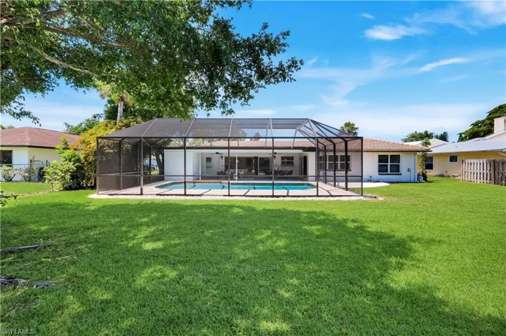 Expansive rear yard featuring a screened pool enclosure with a rectangular swimming pool, concrete decking, and direct access to the interior via sliding glass doors