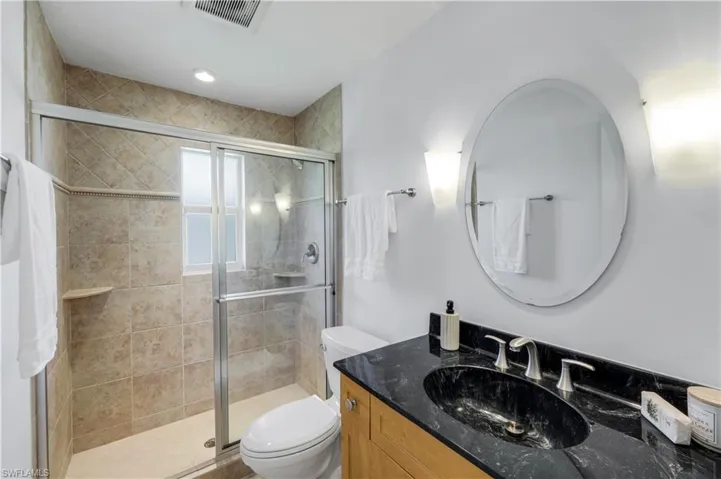 Guest bathroom with shower with sliding glass doors, shower tile to the ceiling, toilet and vanity.