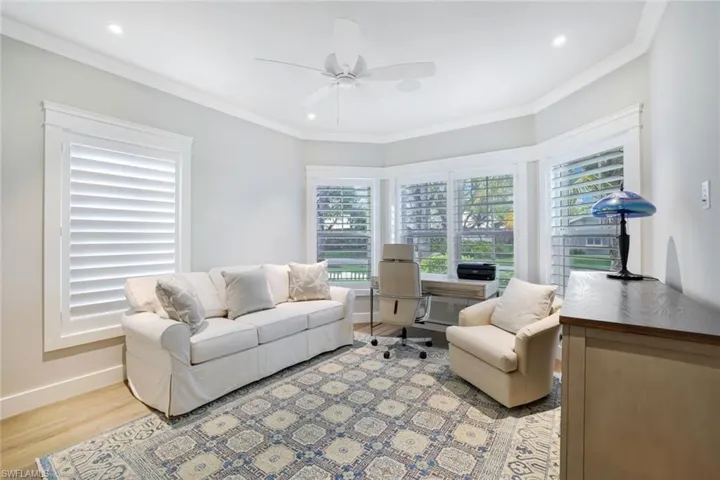Living room with ornamental molding, light wood-type flooring, and ceiling fan