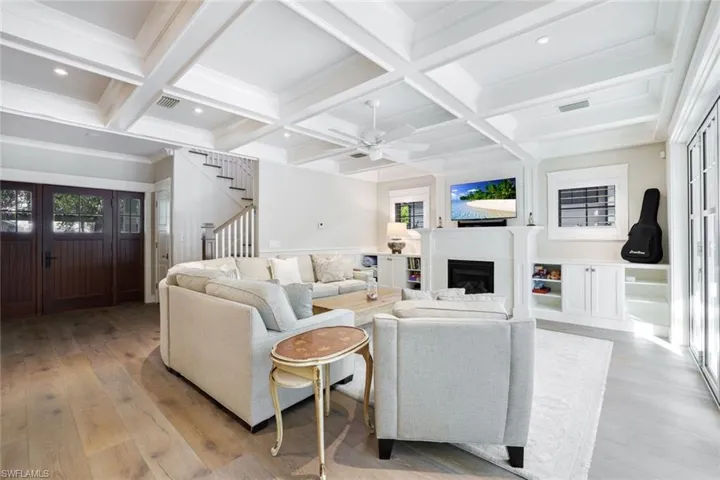 Living room featuring ceiling fan, beam ceiling, light wood-type flooring, and coffered ceiling