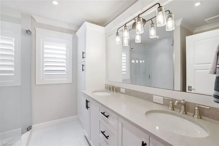 Bathroom with a shower with door, vanity, tile patterned flooring, and crown molding