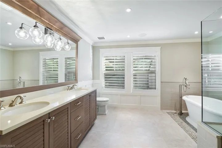 Bathroom with ornamental molding, vanity, a tub, tile patterned flooring, and toilet