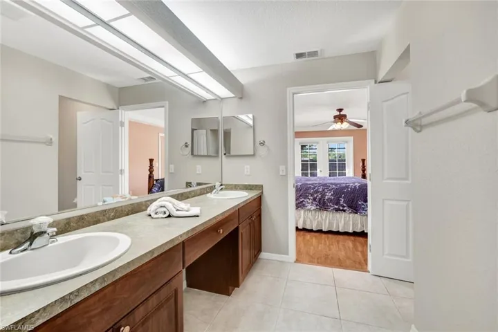 Ensuite bathroom featuring double vanity and light tile patterned flooring.
