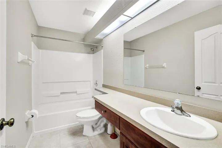 Guest bath with large vanity, shower/tub, and ceramic tile flooring.