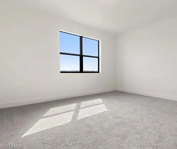 Crisp white walls frame a large window with black gridded panes, offering an expansive outdoor scene