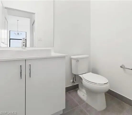 Contemporary bathroom featuring a white vanity with integrated sink, chrome faucet, wall-mounted mirror, and tile flooring