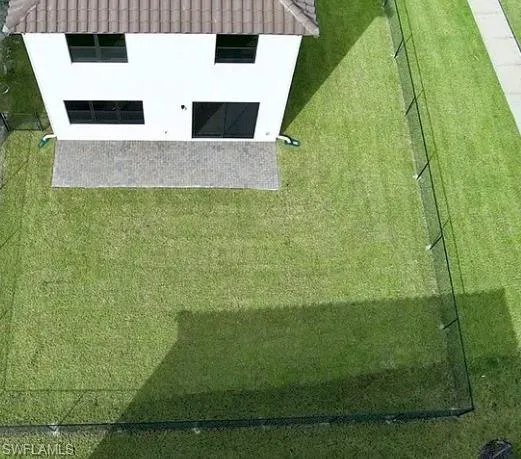 White exterior residence featuring a tiled roof and ample green space