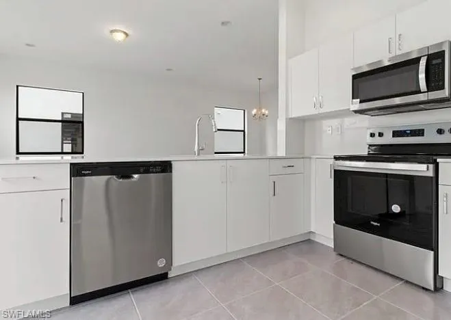 Modern kitchen featuring white cabinetry, stainless steel appliances, light countertops, a stainless steel sink with a gooseneck faucet, and tile flooring