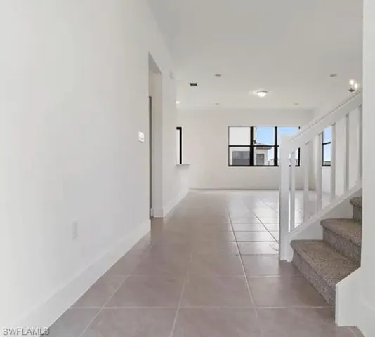 Tiled flooring extending through the entry, with white baseboards and walls