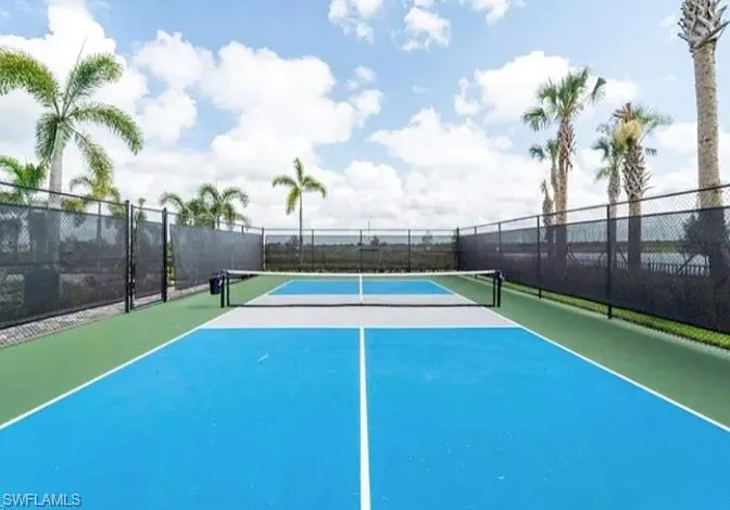 Dedicated pickleball court featuring a blue playing surface with green perimeter, bordered by black chain-link fencing