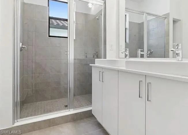Bathroom featuring a glass-enclosed shower with gray tiled walls and a window