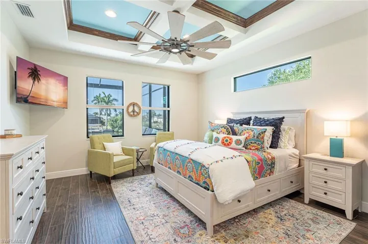 Bedroom with a raised ceiling, ceiling fan, dark hardwood / wood-style flooring, and ornamental molding