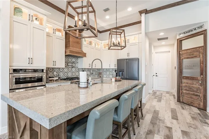 Kitchen featuring a center island with sink, light hardwood / wood-style flooring, appliances with stainless steel finishes, tasteful backsplash, and a kitchen bar
