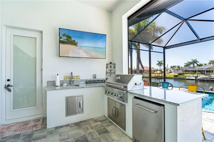 Outdoor Kitchen with pavers, a water view, kitchen peninsula, and fridge.