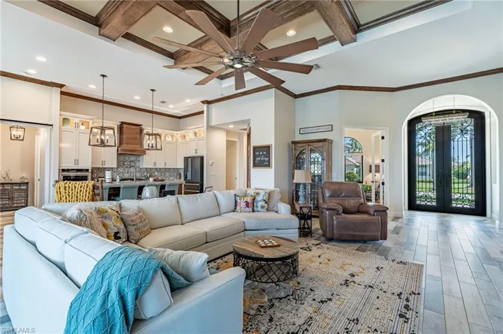 Living room featuring coffered ceiling, ceiling fan, crown molding, and light hardwood / wood-style flooring