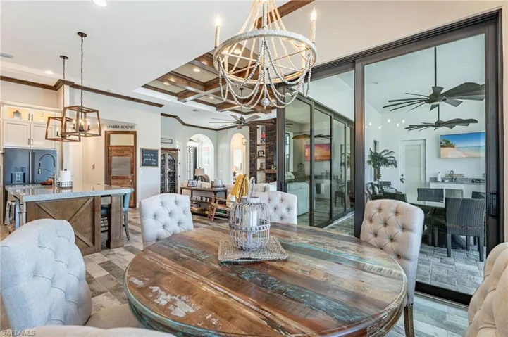 Dining space featuring coffered ceiling, ceiling fan with notable chandelier, beamed ceiling, and ornamental molding