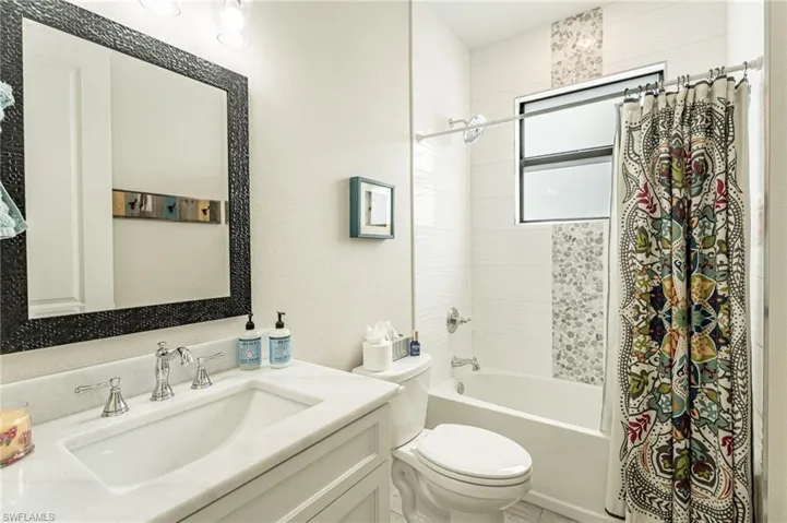Full bathroom featuring shower / bathtub combination with curtain, toilet, and vanity
