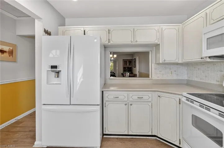 Kitchen with white appliances, light countertops, tasteful backsplash, and light wood finished floors