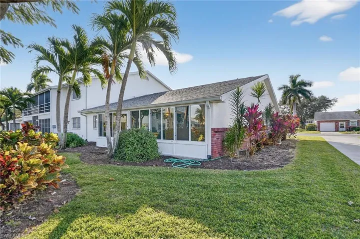 View of home's exterior with stucco siding, a yard, and a sunroom