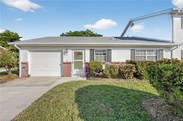 Ranch-style house with brick siding, an attached garage, stucco siding, driveway, and a front lawn